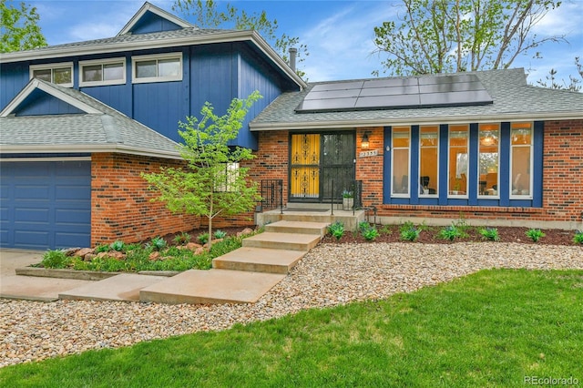 12355 E Arkansas Pl, Aurora, CO 80012 - view of front facade featuring roof mounted solar panels, brick siding, and a shingled roof