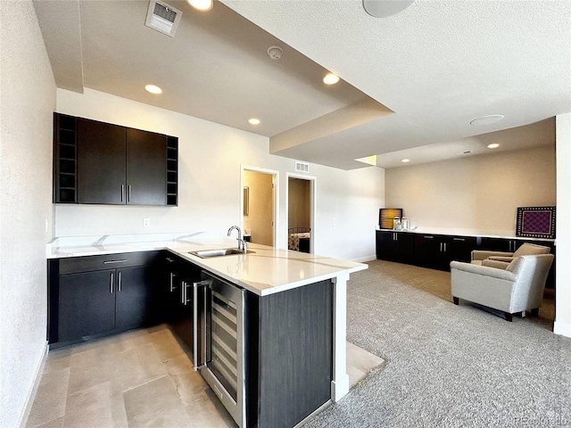 kitchen featuring wine cooler, light colored carpet, kitchen peninsula, and sink