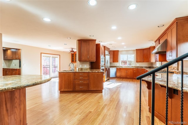 kitchen with ceiling fan, extractor fan, light stone countertops, kitchen peninsula, and light wood-type flooring