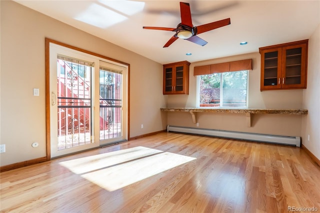 kitchen with kitchen peninsula, ceiling fan, baseboard heating, light stone countertops, and light wood-type flooring