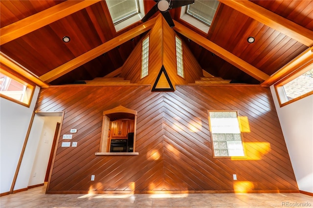 unfurnished living room with a towering ceiling, wooden ceiling, and wood walls