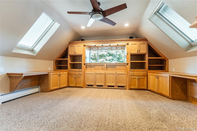 additional living space with a baseboard heating unit, light colored carpet, vaulted ceiling with skylight, and ceiling fan