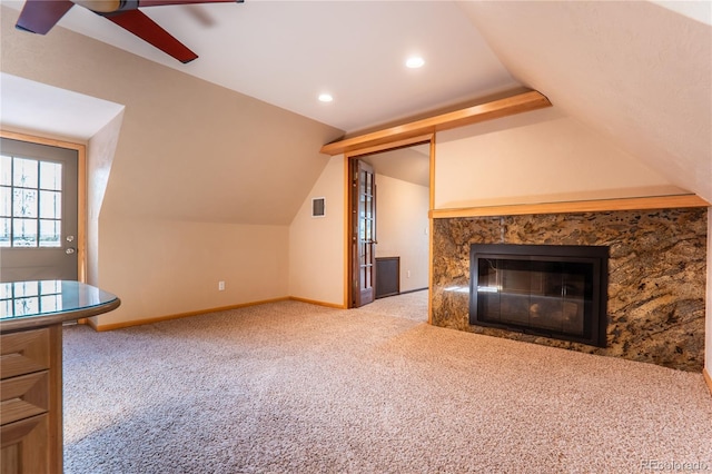 unfurnished living room featuring ceiling fan, vaulted ceiling, light colored carpet, and a high end fireplace