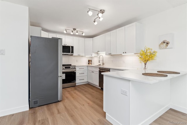 kitchen featuring sink, kitchen peninsula, white cabinets, and stainless steel appliances