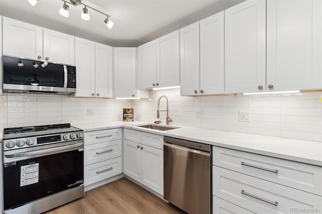 kitchen featuring backsplash, light hardwood / wood-style floors, sink, appliances with stainless steel finishes, and white cabinets