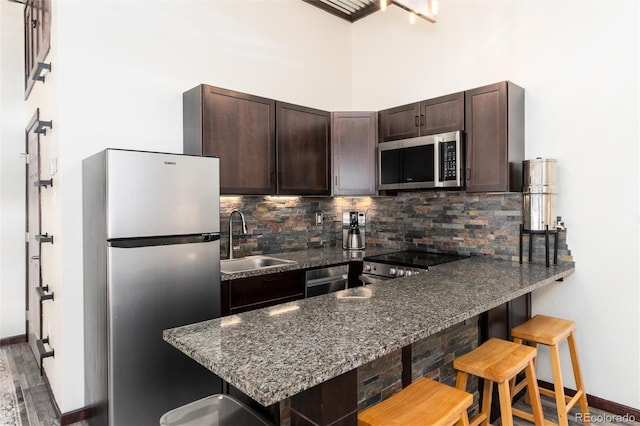 22174 US Highway 6 Unit 7, Dillon, CO 80435 - kitchen with appliances with stainless steel finishes, dark brown cabinets, tasteful backsplash, dark stone countertops, and a peninsula