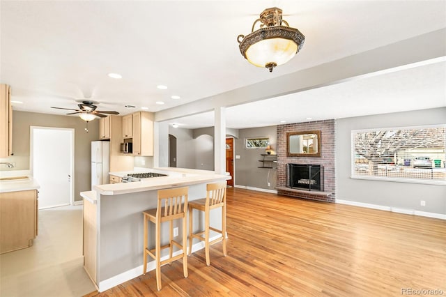 kitchen with white fridge, sink, a kitchen breakfast bar, light hardwood / wood-style floors, and kitchen peninsula