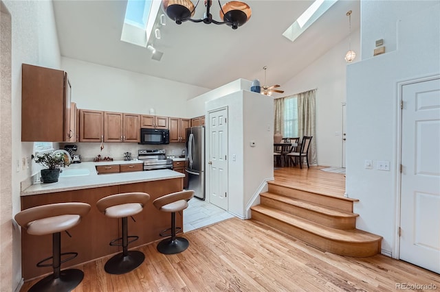 18872 E Prentice Pl, Centennial, CO 80015 - kitchen with a skylight, stainless steel appliances, high vaulted ceiling, light wood finished floors, and light countertops
