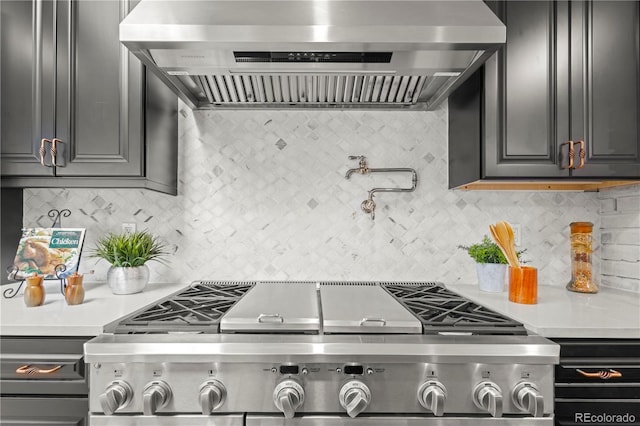 kitchen featuring tasteful backsplash, wall chimney range hood, and stainless steel range oven