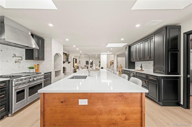 kitchen featuring a large island, a skylight, light hardwood / wood-style floors, and double oven range