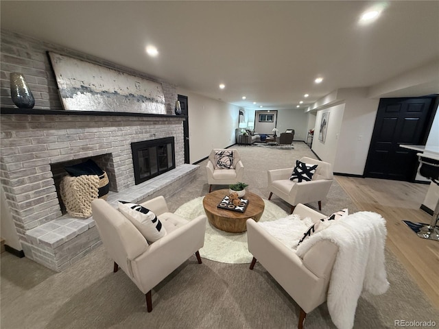 living room with a brick fireplace and light wood-type flooring