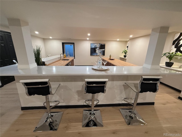 bar featuring light hardwood / wood-style flooring and sink