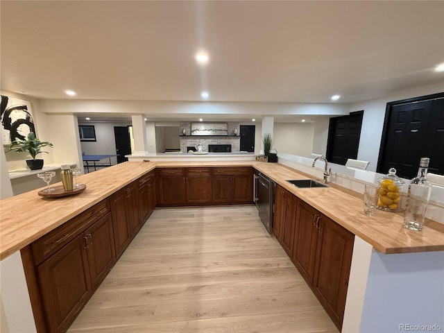 kitchen featuring kitchen peninsula, wood counters, dishwasher, light hardwood / wood-style floors, and sink