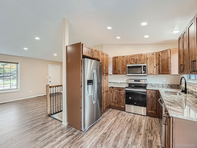 kitchen with light hardwood / wood-style floors, sink, light stone counters, appliances with stainless steel finishes, and lofted ceiling