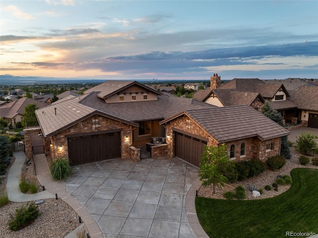 view of front of property with a chimney, concrete driveway, an attached garage, a gate, and stone siding