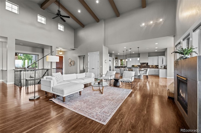 living room with wood finished floors, a tile fireplace, beam ceiling, and baseboards