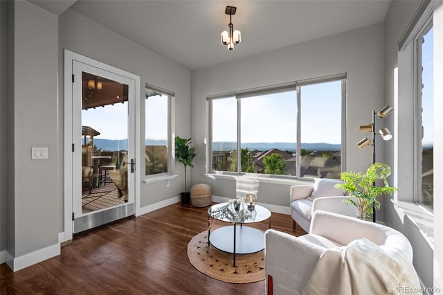 living area featuring a mountain view, a notable chandelier, baseboards, and wood finished floors