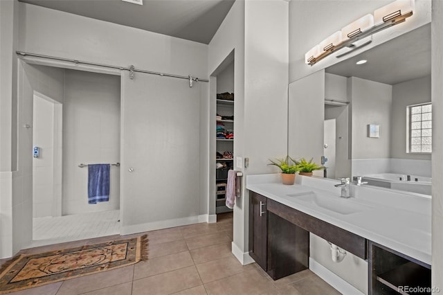 bathroom featuring tile patterned flooring, a walk in closet, a tile shower, and vanity
