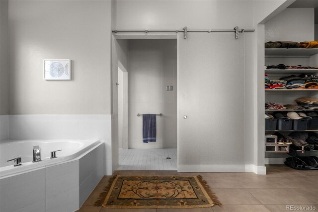 full bath with tiled shower, a garden tub, a walk in closet, and tile patterned floors