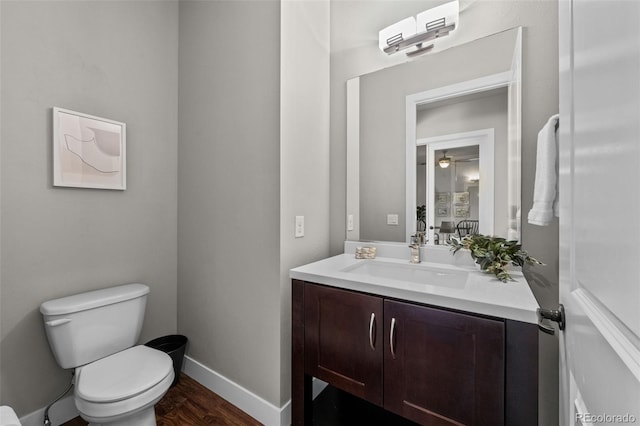 bathroom with wood finished floors, vanity, toilet, and baseboards