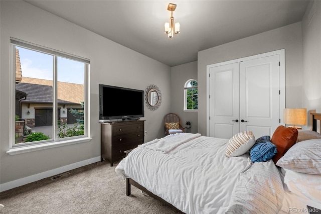carpeted bedroom with a closet, an inviting chandelier, visible vents, and baseboards