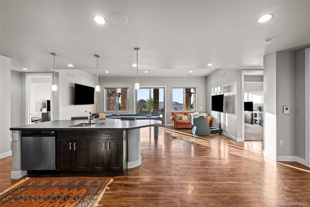 kitchen with a sink, open floor plan, stainless steel dishwasher, dark wood-style floors, and dark countertops