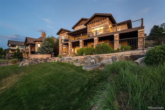 rear view of house featuring stone siding and a yard