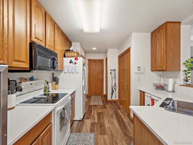 kitchen featuring brown cabinets, recessed lighting, light countertops, wood finished floors, and white appliances