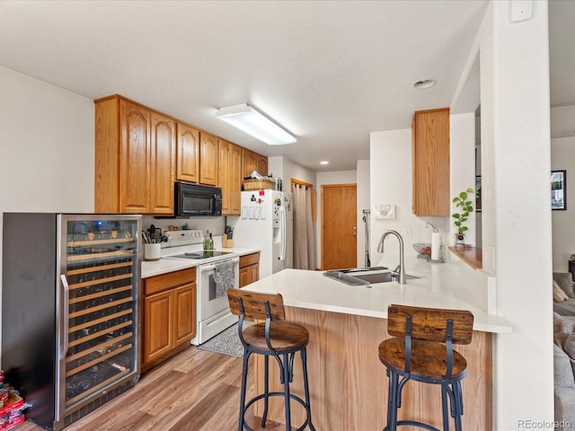 kitchen with a kitchen breakfast bar, a sink, beverage cooler, white appliances, and a peninsula