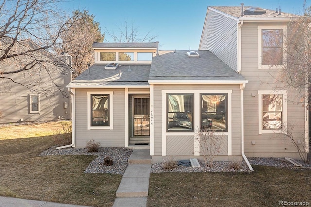 view of front facade featuring a front yard and roof with shingles