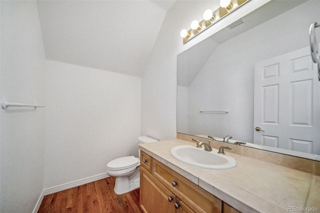 half bath with lofted ceiling, wood finished floors, toilet, vanity, and baseboards