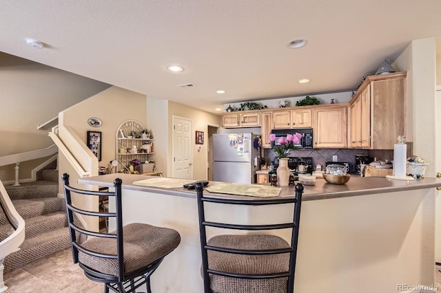 12835 Mayfair Way Unit C, Englewood, CO 80112 - kitchen featuring freestanding refrigerator, black microwave, light brown cabinets, a kitchen bar, and recessed lighting