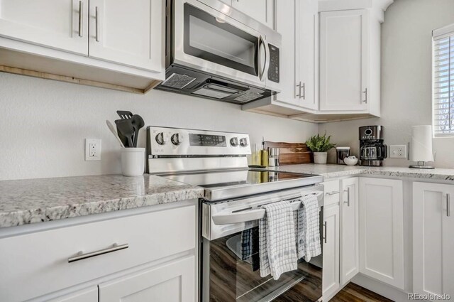 kitchen featuring dark wood-style flooring, appliances with stainless steel finishes, and white cabinetry