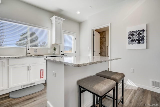 kitchen with a kitchen bar, light wood-style floors, and visible vents