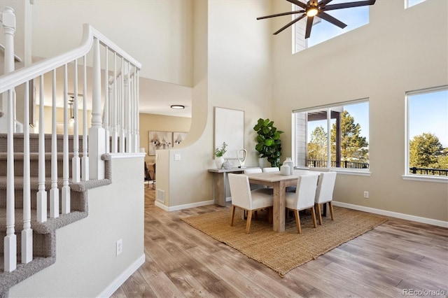 dining room featuring ceiling fan, wood-type flooring, and a high ceiling