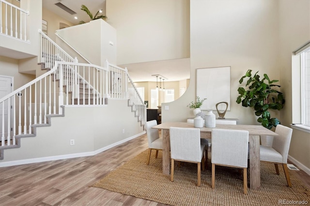 dining room featuring a towering ceiling and hardwood / wood-style floors