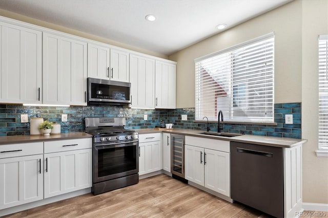 kitchen with white cabinets, stainless steel appliances, beverage cooler, and sink