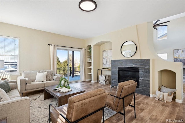 living room featuring a fireplace, built in features, and light hardwood / wood-style flooring