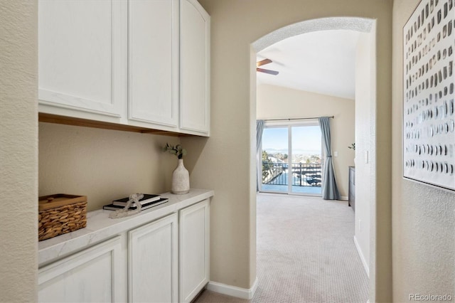 hallway featuring lofted ceiling and light colored carpet