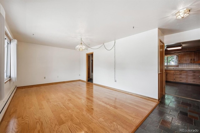 209 S 13th Ave, Brighton, CO 80601 - unfurnished room featuring a baseboard radiator, a chandelier, and baseboards