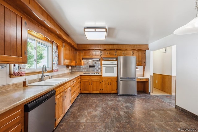 209 S 13th Ave, Brighton, CO 80601 - kitchen with appliances with stainless steel finishes, a sink, brown cabinets, backsplash, and light countertops