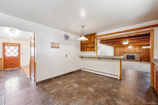 209 S 13th Ave, Brighton, CO 80601 - kitchen with a baseboard heating unit, a peninsula, open shelves, a fireplace with raised hearth, and light countertops