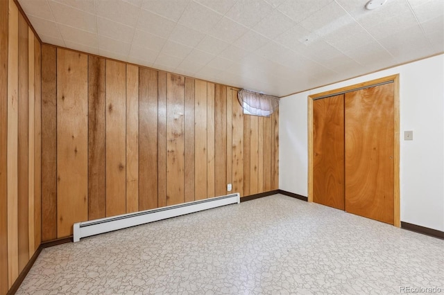 209 S 13th Ave, Brighton, CO 80601 - unfurnished bedroom with baseboard heating, baseboards, wood walls, and a closet