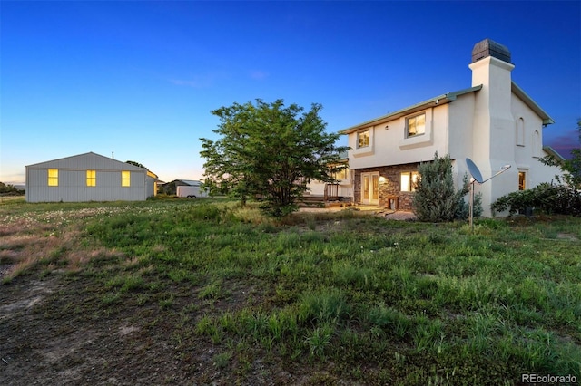 4627 Cathy Ln, Erie, CO 80516 - back of house at dusk featuring a chimney and stucco siding