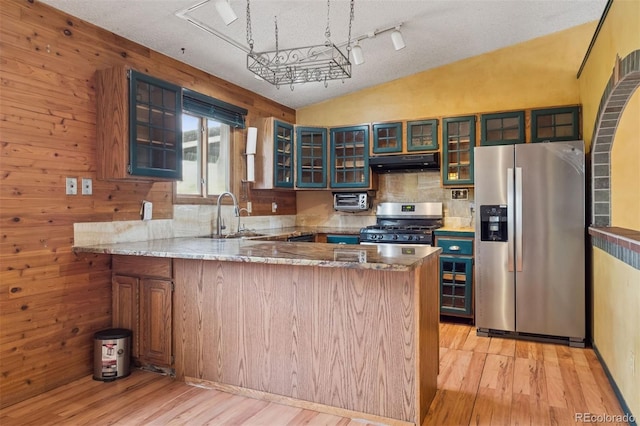 4627 Cathy Ln, Erie, CO 80516 - kitchen featuring appliances with stainless steel finishes, under cabinet range hood, a peninsula, light wood finished floors, and vaulted ceiling