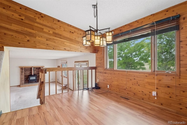 4627 Cathy Ln, Erie, CO 80516 - empty room featuring wooden walls, wood finished floors, a chandelier, and a wood stove