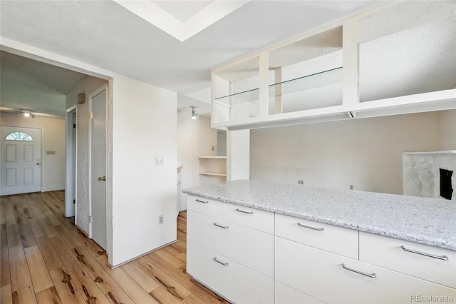 kitchen featuring light wood-style flooring, white cabinetry, light stone counters, and open shelves