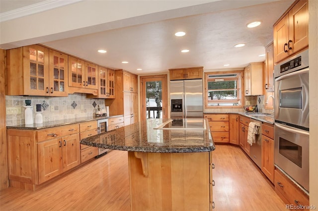 kitchen featuring a breakfast bar, stainless steel appliances, sink, light hardwood / wood-style flooring, and a kitchen island