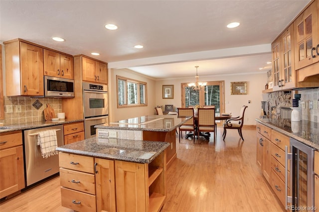 kitchen featuring light wood-type flooring, ornamental molding, stainless steel appliances, beverage cooler, and a center island