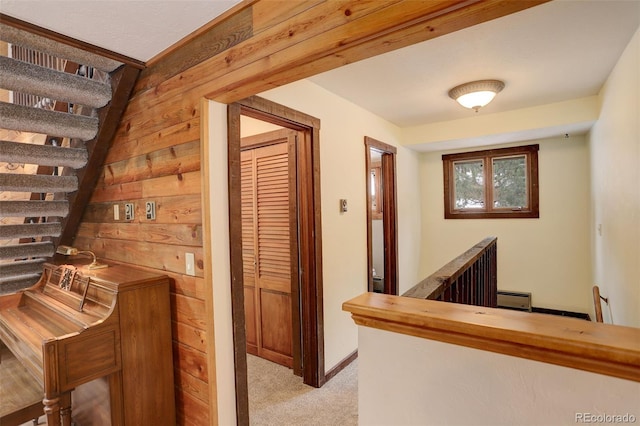 hallway featuring light carpet, a baseboard heating unit, and wood walls